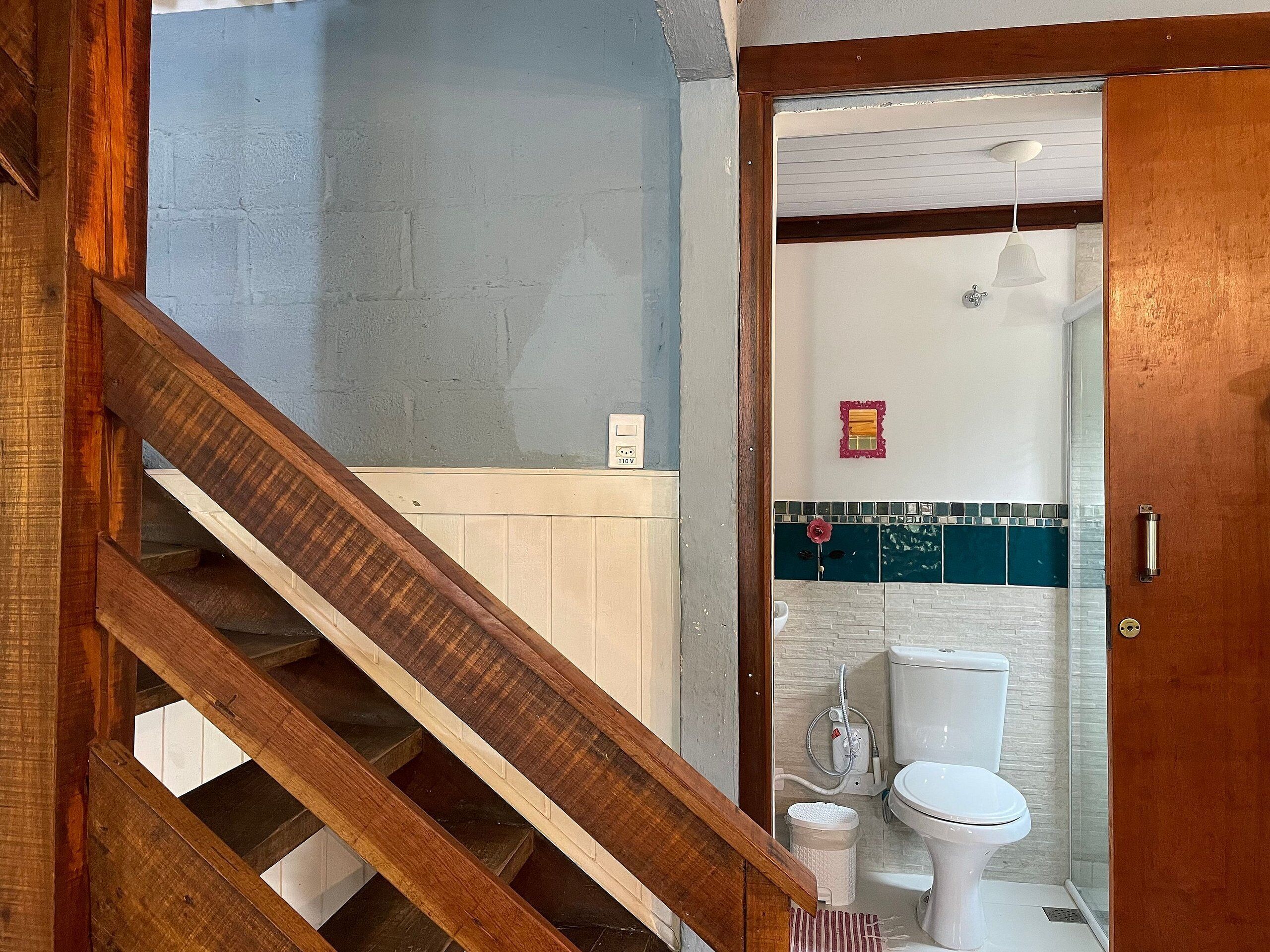 A bathroom with a toilet, shower, and a small mirror.