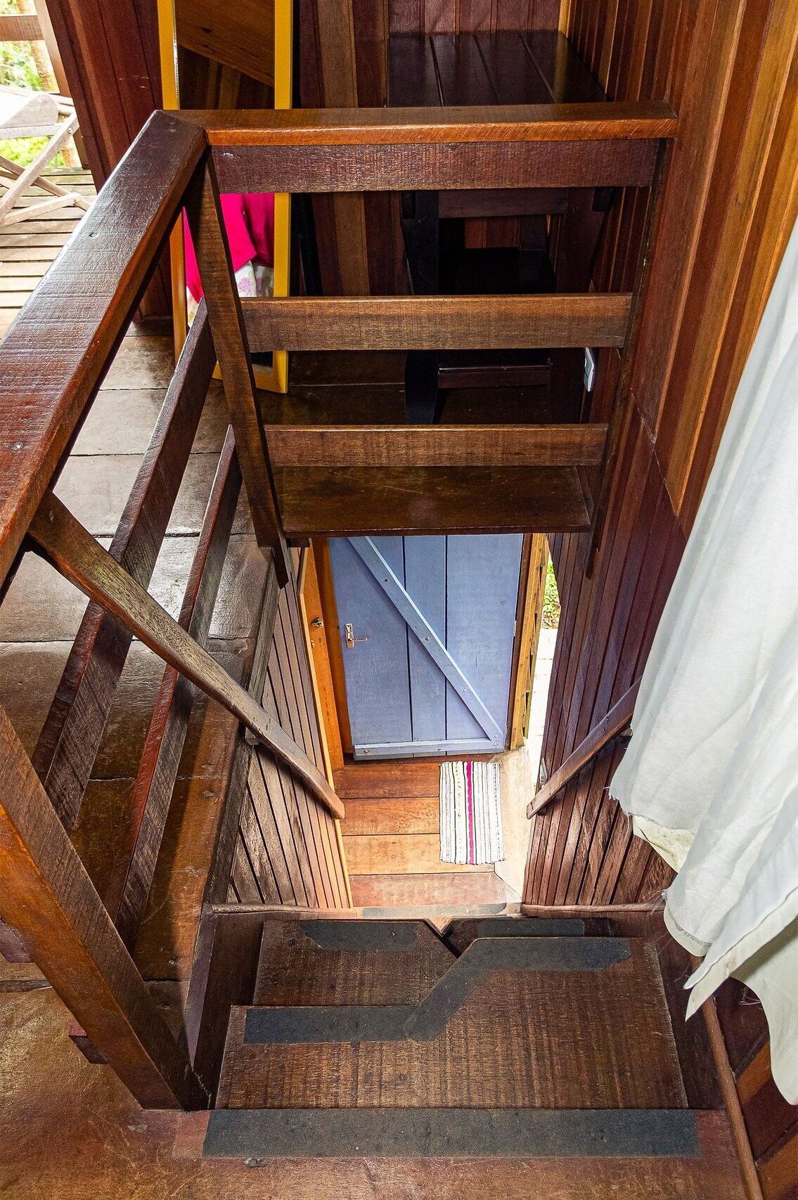 Un escalier en bois mène à une porte qui donne sur un ciel bleu.