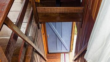 Un escalier en bois mène à une porte qui donne sur un ciel bleu.