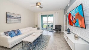 A modern living room with a white sofa, a coffee table, a TV, and a ceiling fan. - (FR304) Storey Lake Condo 2/2, Free Waterpark (Kissimmee)