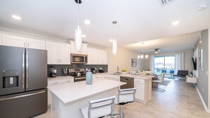 A modern kitchen with white cabinets, stainless steel appliances, and a central island with bar stools. - (FR304) Storey Lake Condo 2/2, Free Waterpark (Kissimmee)