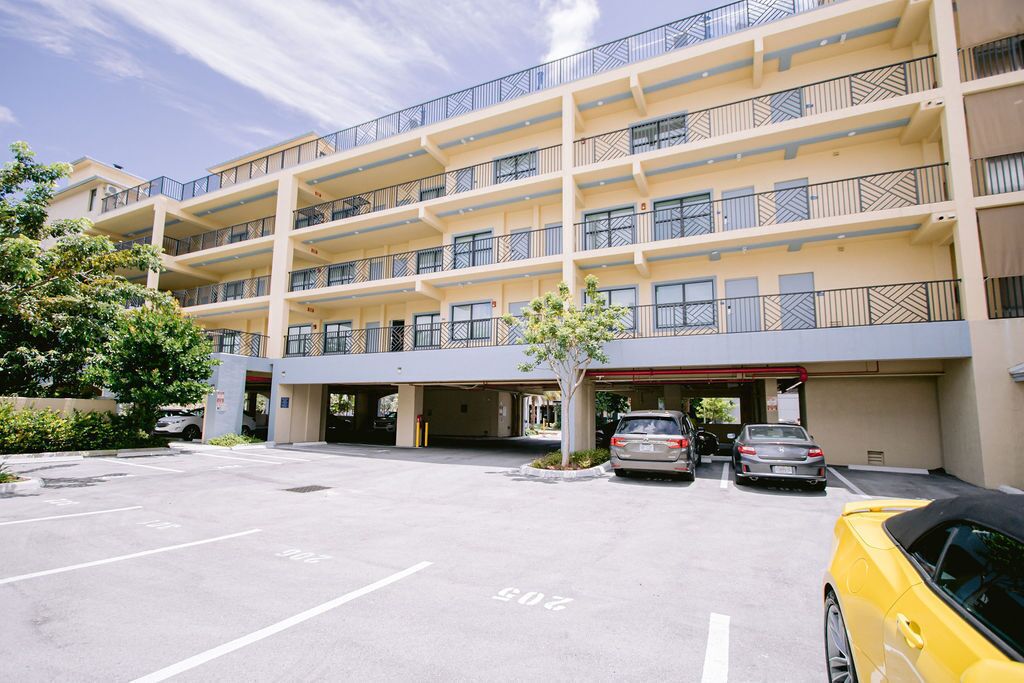 Un hotel de varios pisos con un estacionamiento y varios coches aparcados.