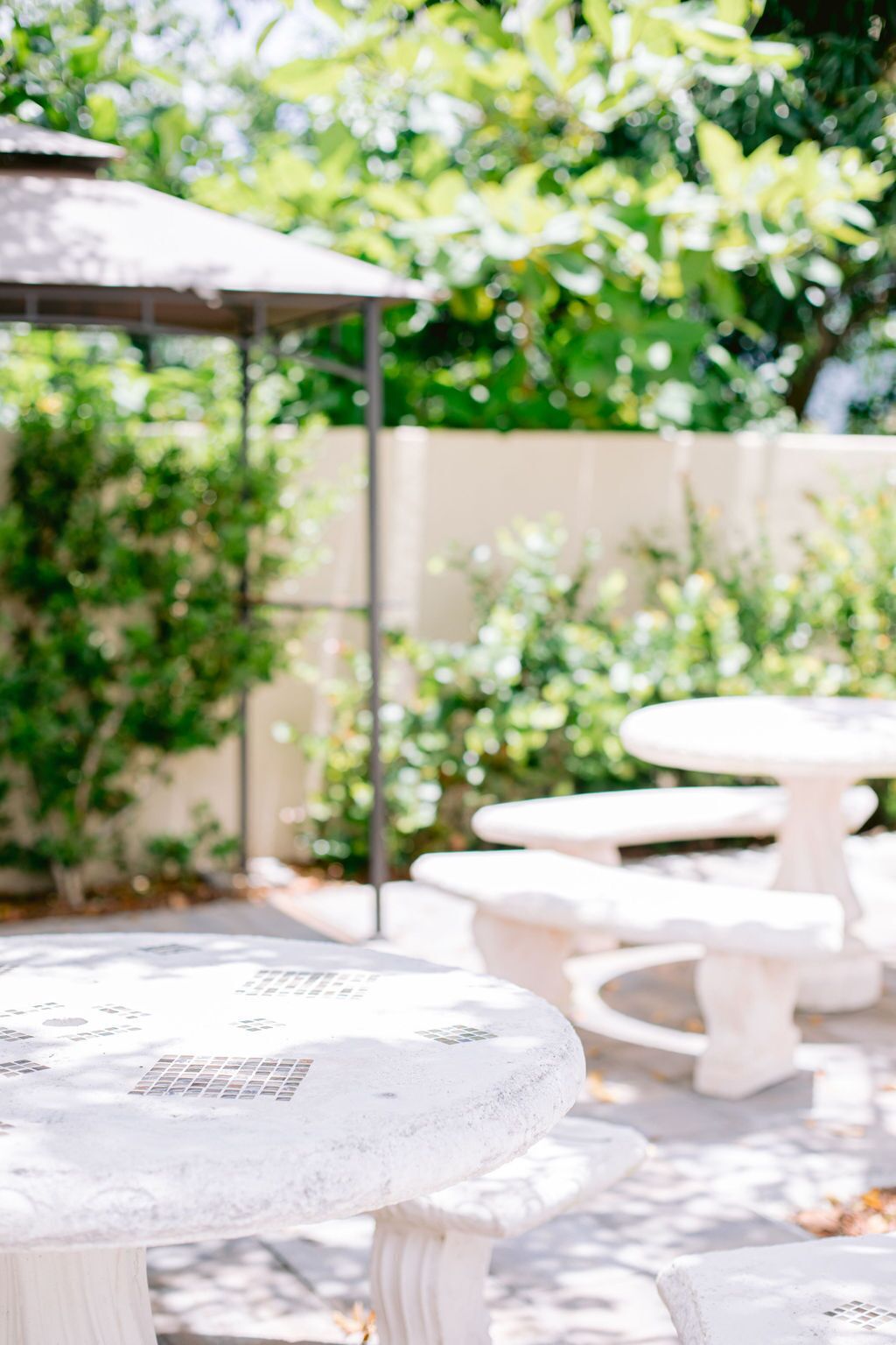 A patio area with white stone tables and a covered seating area.