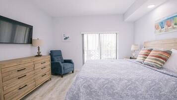 Une chambre à coucher avec un lit, une commode, une chaise, une fenêtre avec des stores et un tableau accroché au mur.