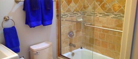 A bathroom with a toilet, a glass-enclosed shower, and a bathtub.