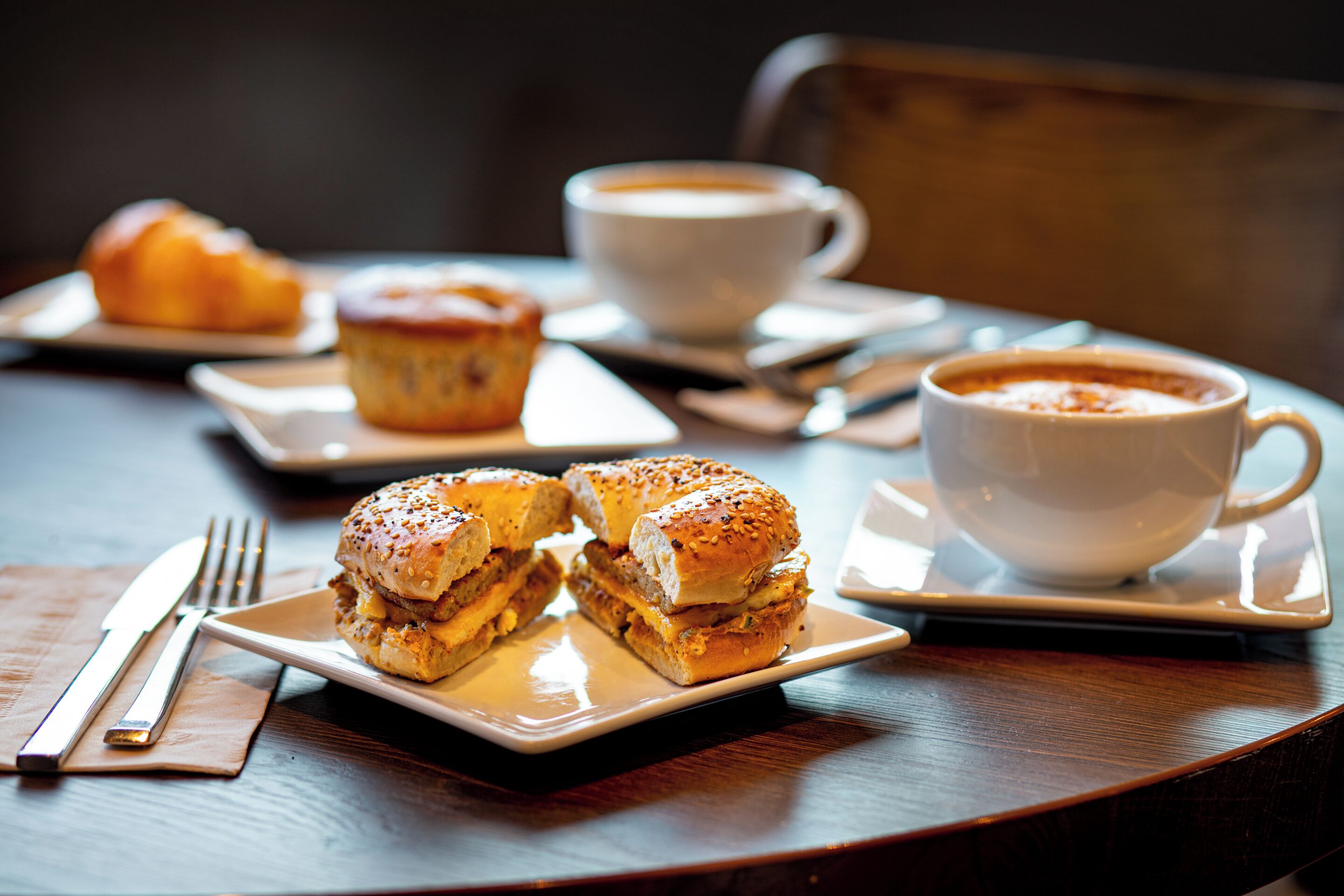 A table with a sandwich, a muffin, and a cup of coffee.