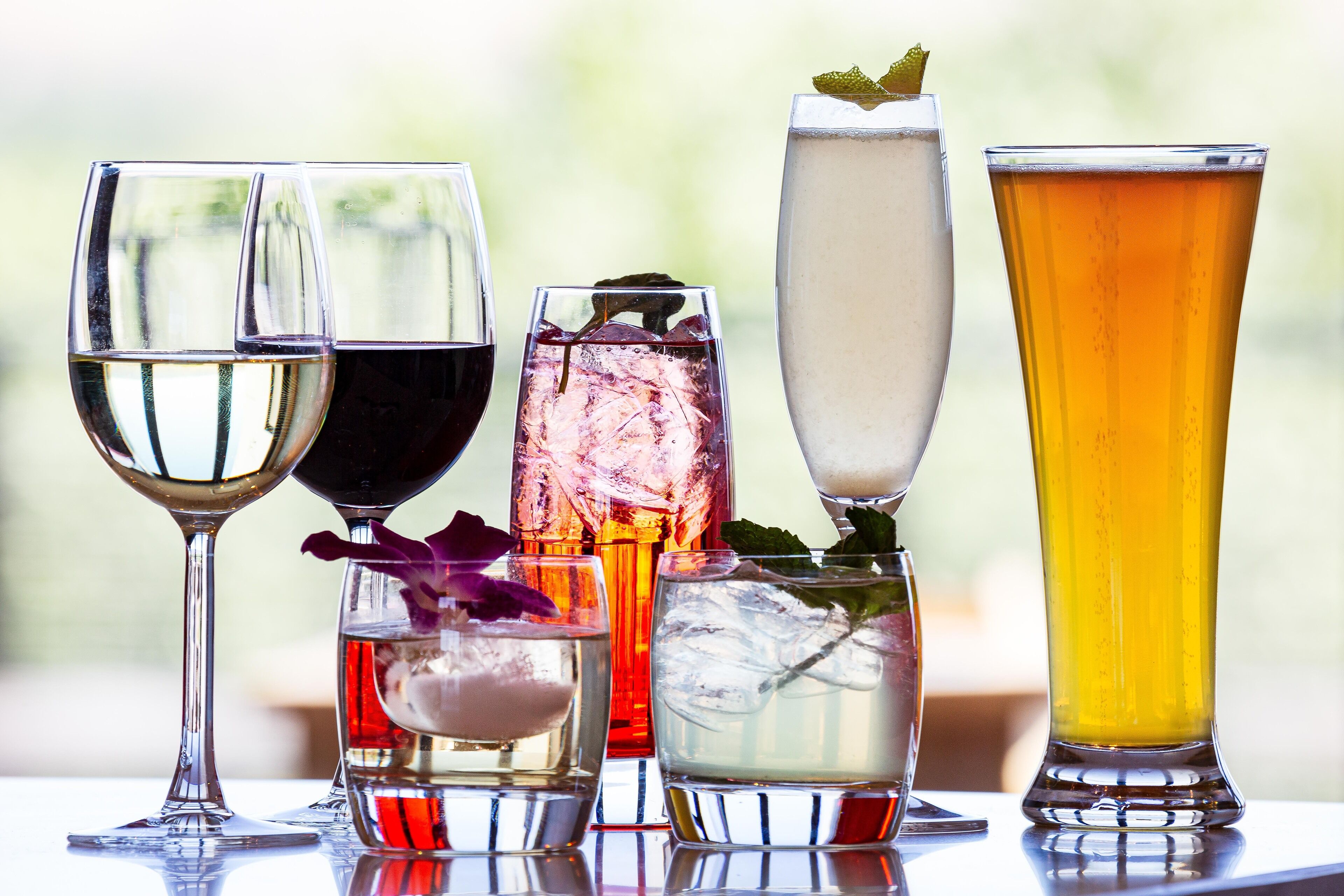 A variety of drinks in different glassware on a table.