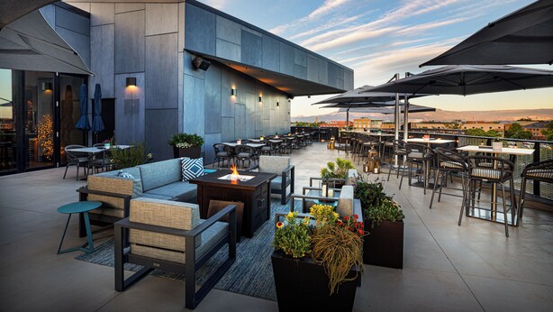 An outdoor patio area with seating arrangements, tables, and umbrellas. - Hotel Maverick (Grand Junction)