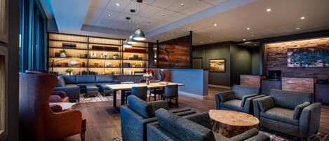 A modern lounge area with sofas, a dining table, and a bookshelf.