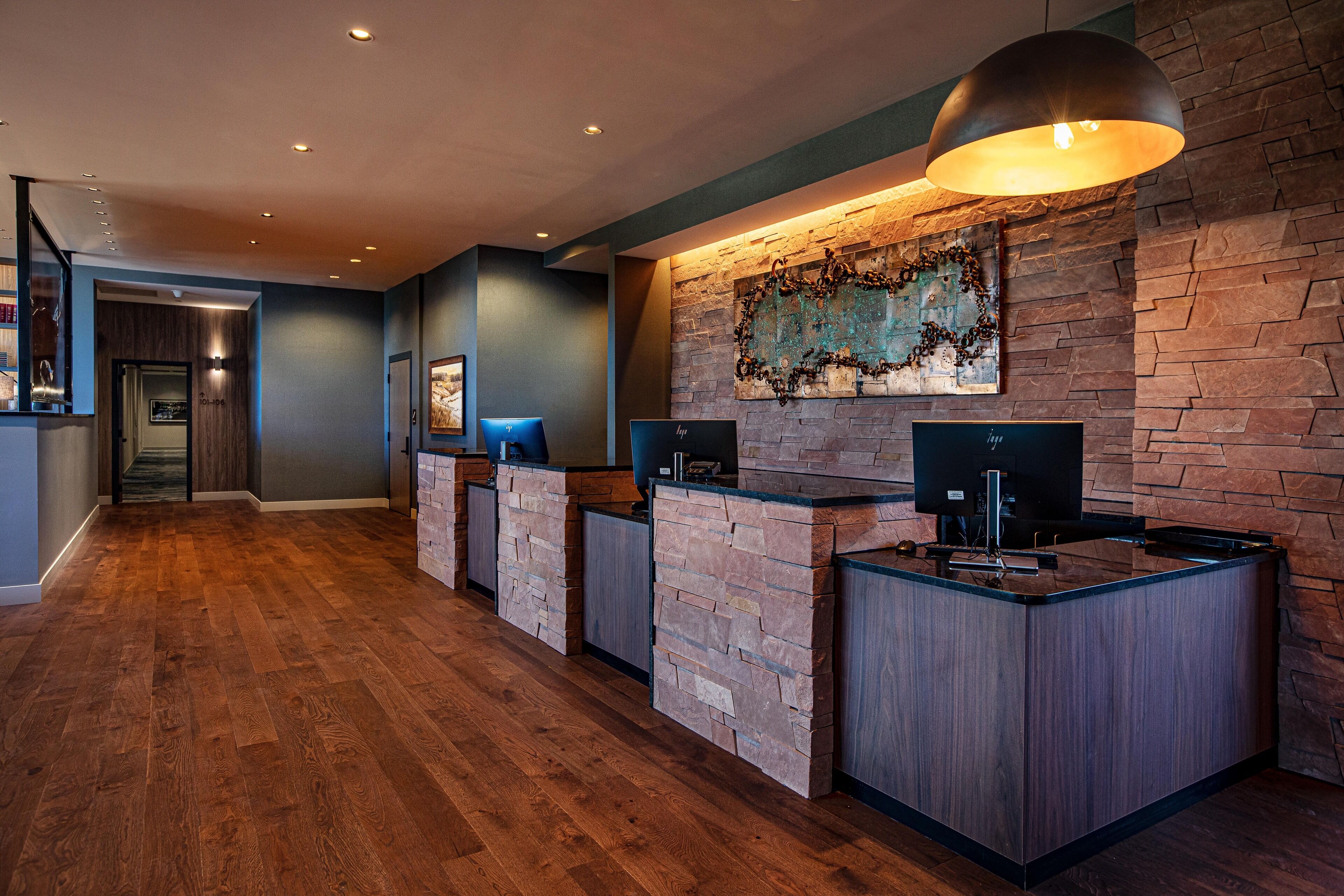 A reception area with a stone wall, a large pendant light, and a flat-screen TV.