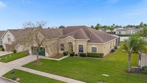 A residential house with a well-maintained lawn, a driveway, and a garage. - Fun Family Escape: 6 BR Oasis w/Private South-Facing Pool! (Davenport)