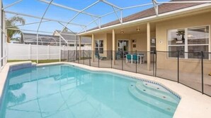 A swimming pool with a glass enclosure, a covered patio area with outdoor seating, and a view of the surrounding neighborhood. - Fun Family Escape: 6 BR Oasis w/Private South-Facing Pool! (Davenport)