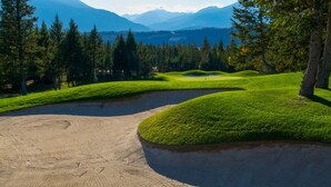 A golf course with a sand bunker and a pond. - Headwaters Lodge at Eagle Ranch Resort (Invermere)