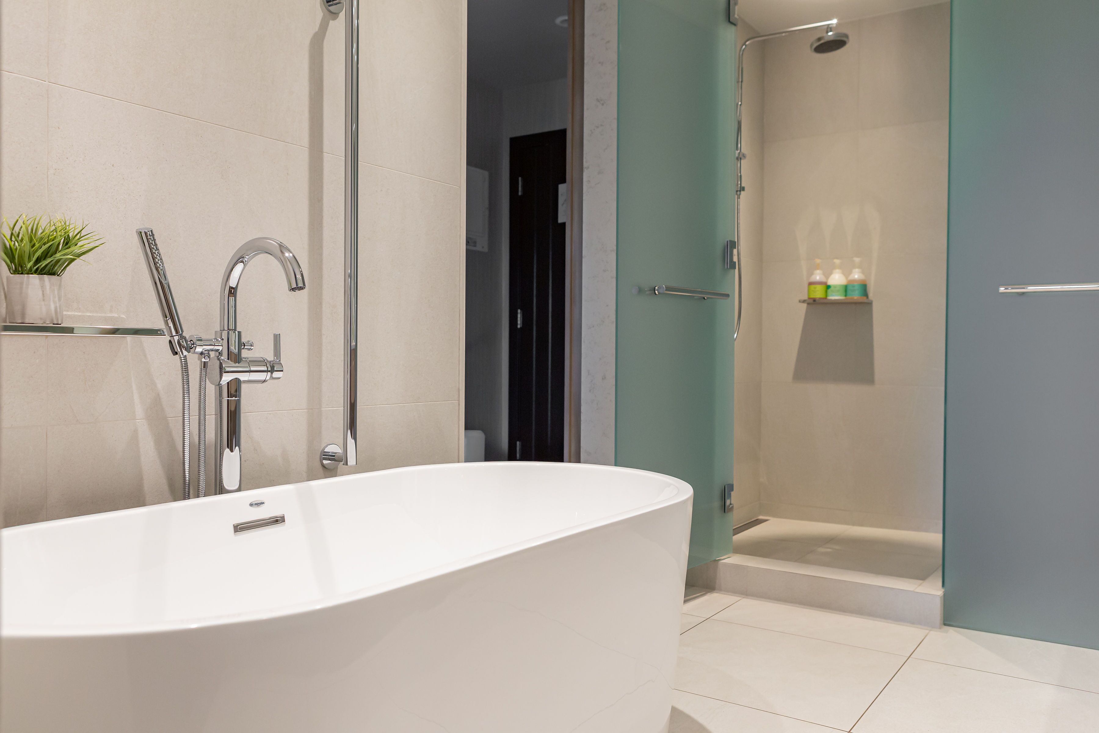 A modern bathroom with a freestanding bathtub, a glass-enclosed shower, and a shelf with toiletries.