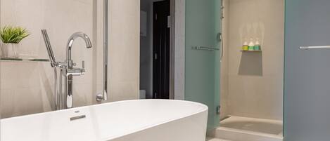 A modern bathroom with a freestanding bathtub, a glass-enclosed shower, and a shelf with toiletries.