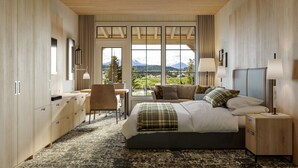 A modern hotel room with a large bed, a desk, and a view of mountains. - Headwaters Lodge at Eagle Ranch Resort (Invermere)