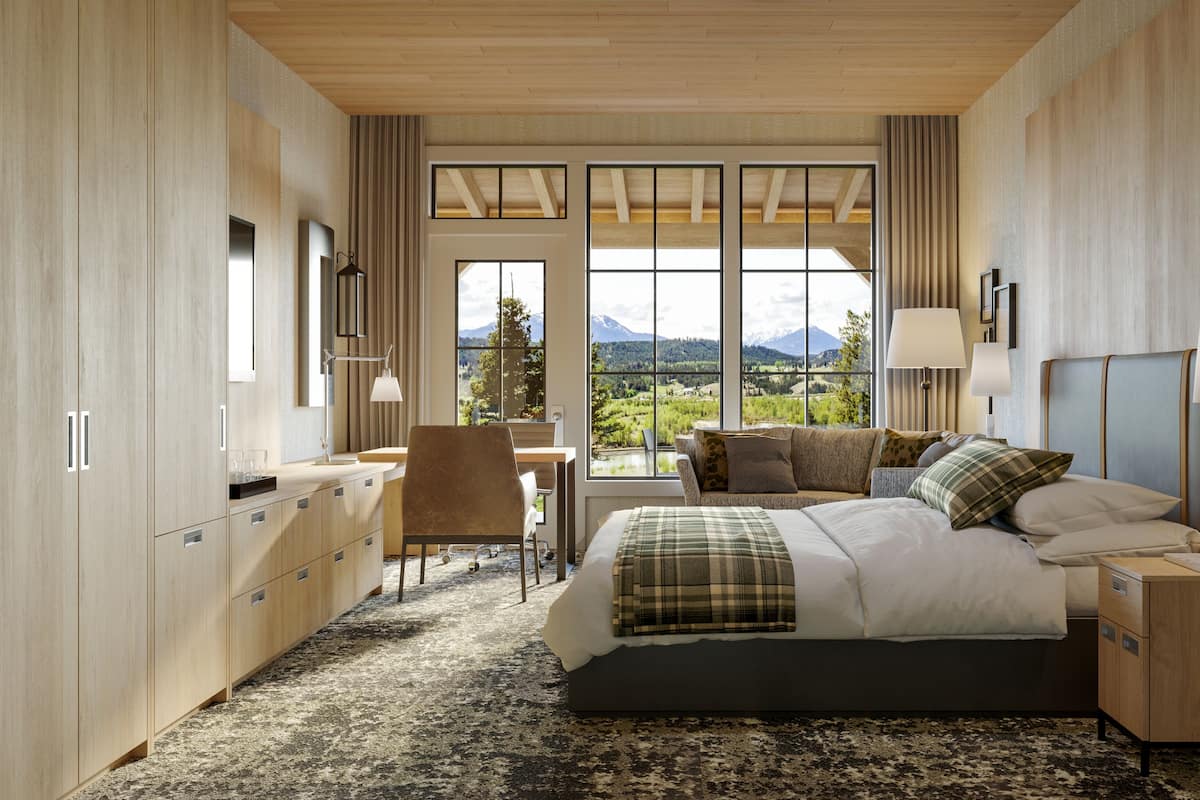 A modern hotel room with a large bed, a desk, and a view of mountains.