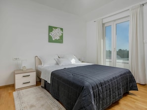 Een slaapkamer met een bed, nachtkastje en een raam met gordijnen.