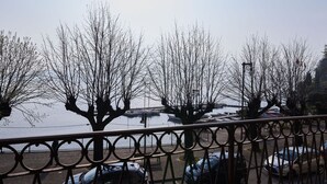 A view of a parking area with cars and leafless trees, a body of water, and a metal fence. - Beautiful apartment for 6 guests with WIFI, TV, balcony and pets allowed (Dongo)