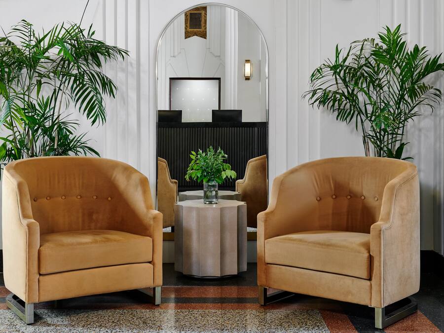 A lobby with two armchairs, a round table, and a mirror.