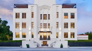 Un bâtiment blanc avec une entrée centrale, de nombreuses fenêtres et un drapeau au sommet.