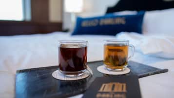 A tray with two glasses of tea on a bed with white sheets and a blue pillow in the background.