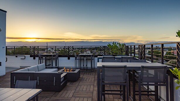 Une terrasse sur le toit avec des sièges extérieurs, un foyer et une vue sur le coucher de soleil sur les montagnes.