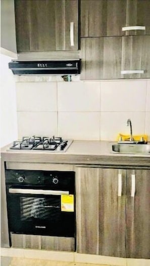 Kitchen area with gas stove, black oven, and stainless steel sink.