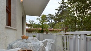 Ein Balkon im Freien mit einem Tisch für zwei Personen, weißen Stühlen und einem weißen Geländer.