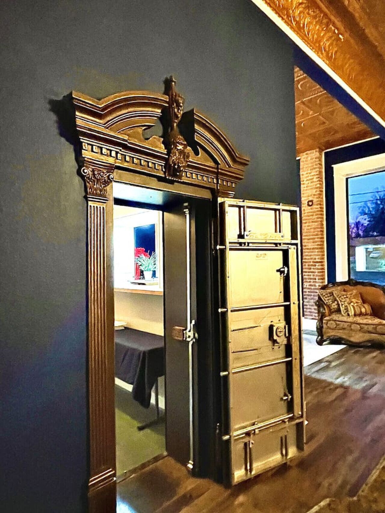 Une pièce avec un grand buffet richement décoré adossé à un mur sombre, un plafond en bois et un mur en briques.