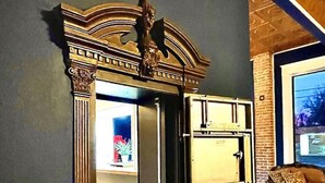 A room with a large, ornate cabinet against a dark wall, a wooden ceiling, and a brick wall. - The Miser Lodge and/or Event Center (Cotter)