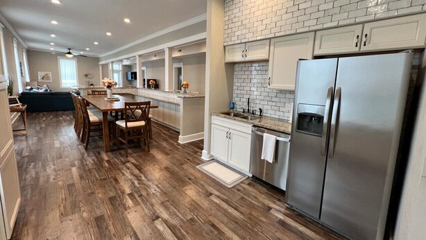A spacious kitchen with a large island, white cabinetry, and a stainless steel refrigerator. - The Miser Lodge and/or Event Center (Cotter)