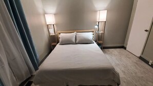 Quarto de hotel com uma cama de solteiro, duas luminárias de cabeceira e uma porta.
