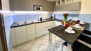 Uma cozinha moderna com armários cinzas, micro-ondas, pia e uma área de refeições com mesa posta para dois.