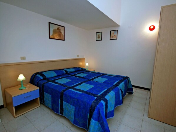A bedroom with a bed, two bedside tables, a nightstand, and a wardrobe.
