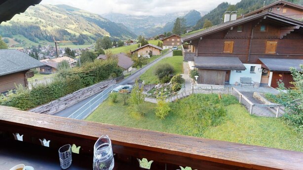 A wooden house with a balcony overlooking a valley with houses and mountains. - Beautiful apartment for 4 guests with TV, balcony and pets allowed (Lenk)