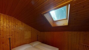 A wooden room with a bed, a chair, and a skylight. - Beautiful apartment for 4 guests with TV, balcony and pets allowed (Lenk)
