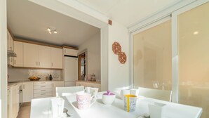 Una cucina moderna con mobili bianchi, un tavolo da pranzo apparecchiato con stoviglie bianche e decorate, e un'ampia finestra con vista.