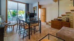 Un soggiorno moderno con un tavolo da pranzo in vetro, posti a sedere confortevoli, una cassettiera in legno e una scala che conduce a un altro piano.