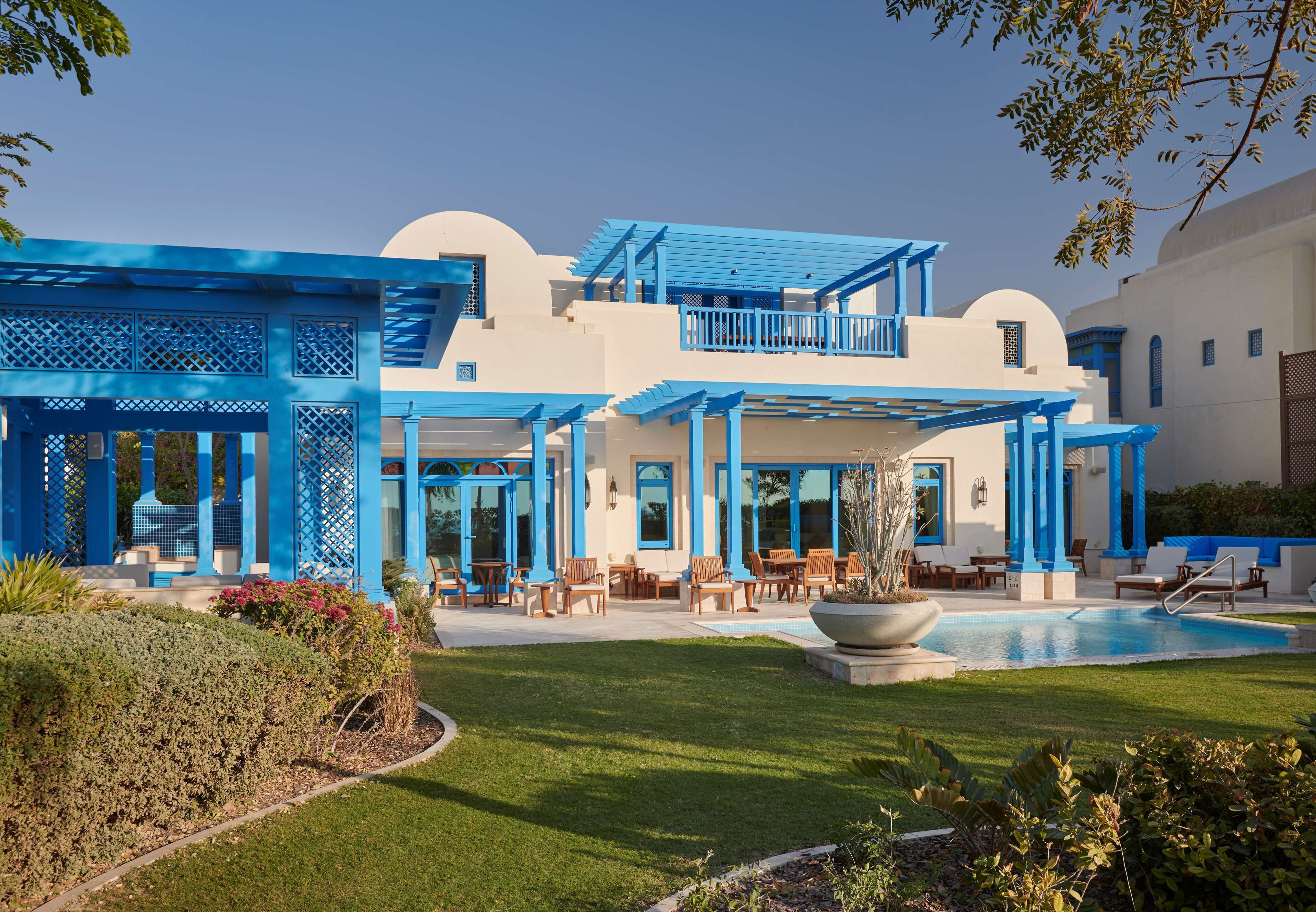 A two-story building with a pool, outdoor seating, and a well-maintained lawn.