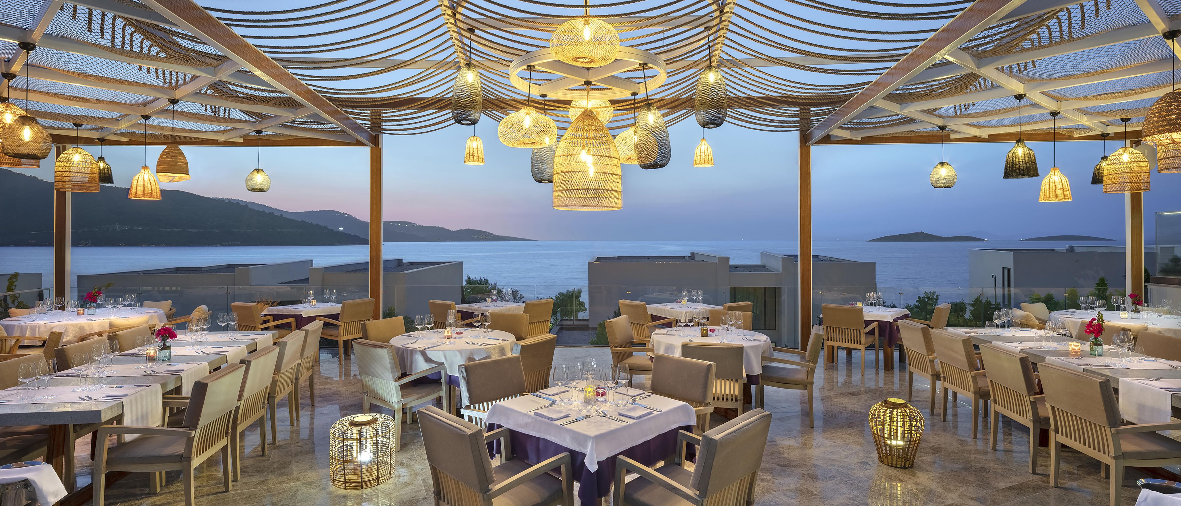 A restaurant with tables set for dining, overlooking a body of water.