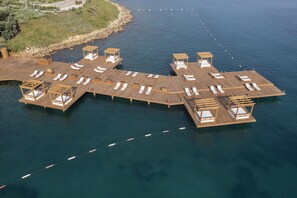 A wooden pier extending into a body of water with multiple sun loungers and wooden structures. - Susona Bodrum, LXR Hotels & Resorts (Bodrum)