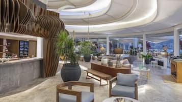 Amplia sala de estar con un diseño moderno, que incluye un bar, arreglos de asientos y grandes ventanales con vistas al exterior.