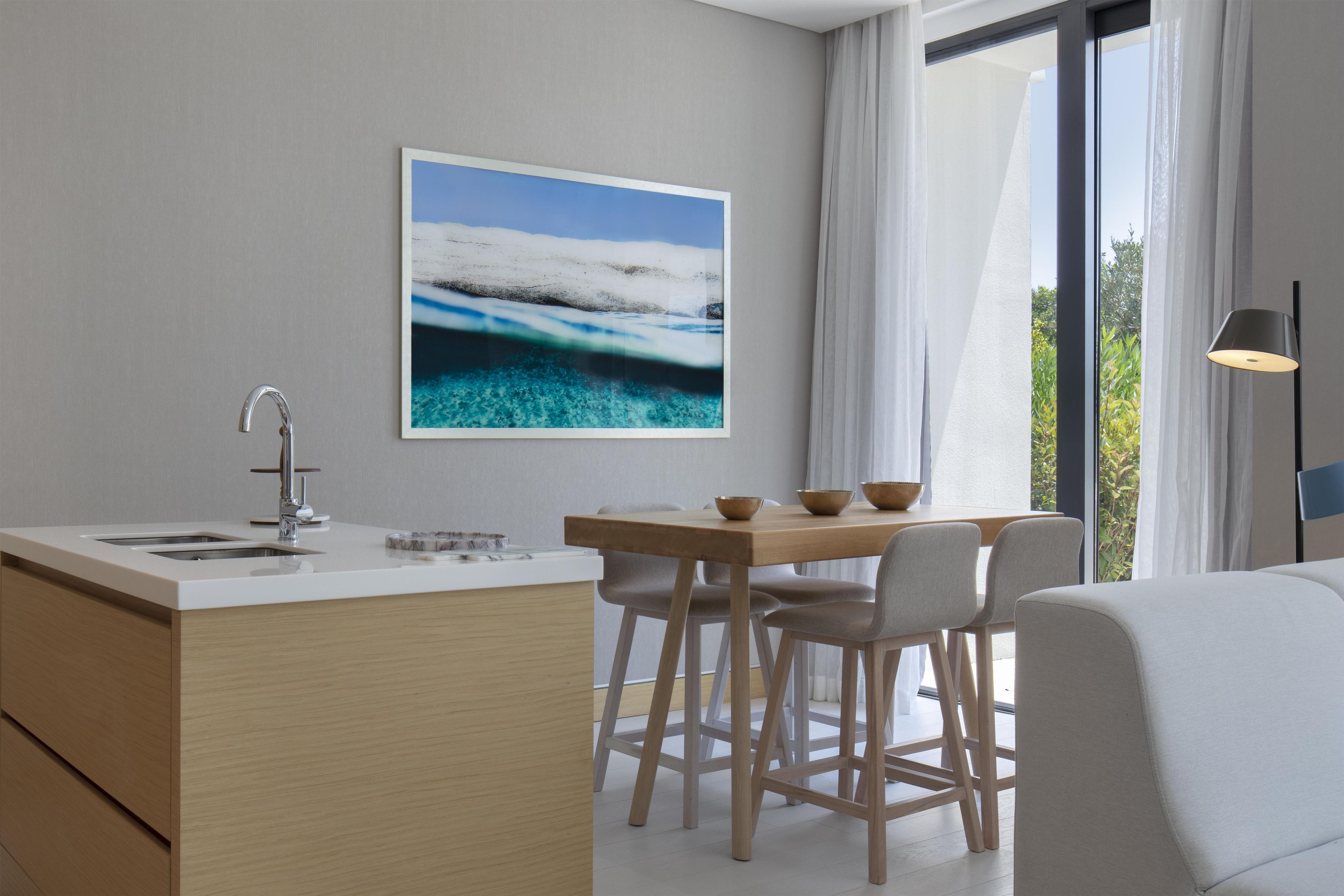 Una cocina moderna con encimera blanca, pileta de acero inoxidable y armarios de madera.