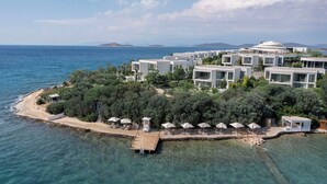 A coastal resort with modern villas, a pier, and clear blue waters.