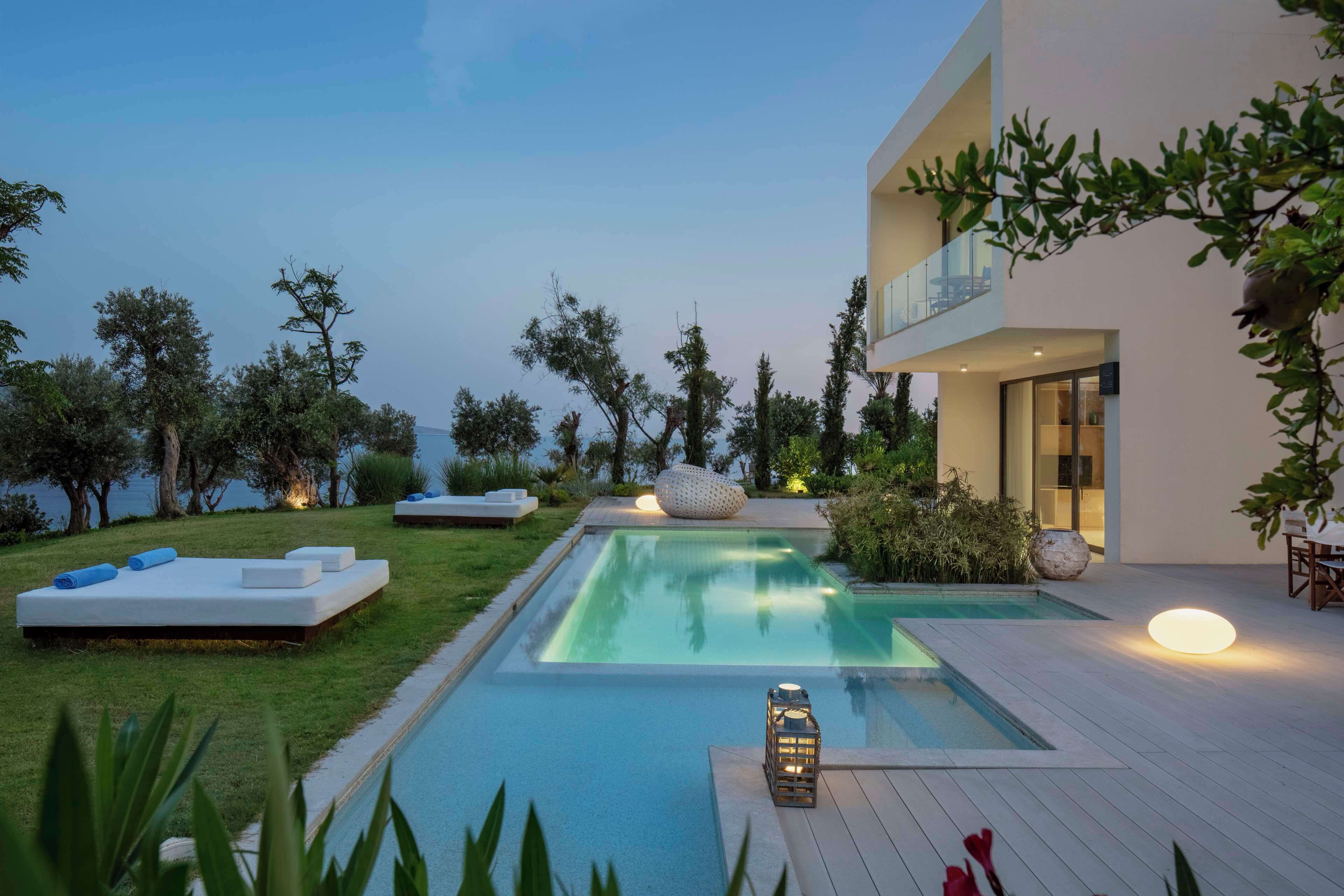 Un área de piscina exterior moderna con un diseño minimalista, que incluye una plataforma flotante y sillones de descanso.