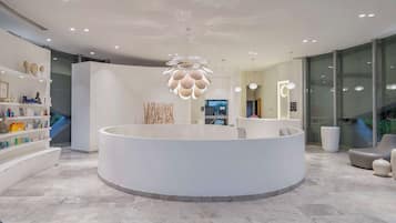Experience the elegant lobby, featuring a central reception desk, curved seating area, and a stunning chandelier.