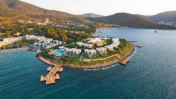 Vista aérea de un complejo turístico costero con villas, una piscina y un muelle.