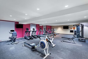 Ett modernt gym med olika konditionsmaskiner, styrketräningsutrustning och en träningsbänk.