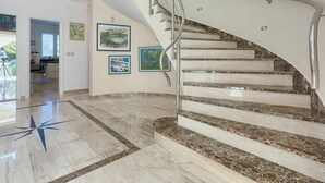 Un intérieur moderne avec un escalier à volutes, un revêtement de sol en marbre et des œuvres d’art accrochées aux murs.